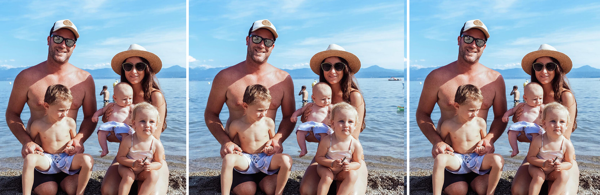 A family of four sits on a beach, with a baby in the mother's arms and two young children beside them.