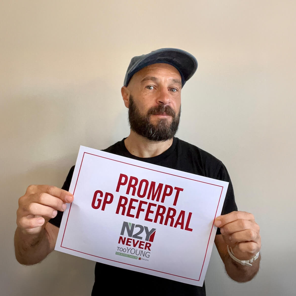 A man with a beard and cap holds a sign that reads "PROMPT GP REFERRAL N2Y NEVER tooYOUNG."