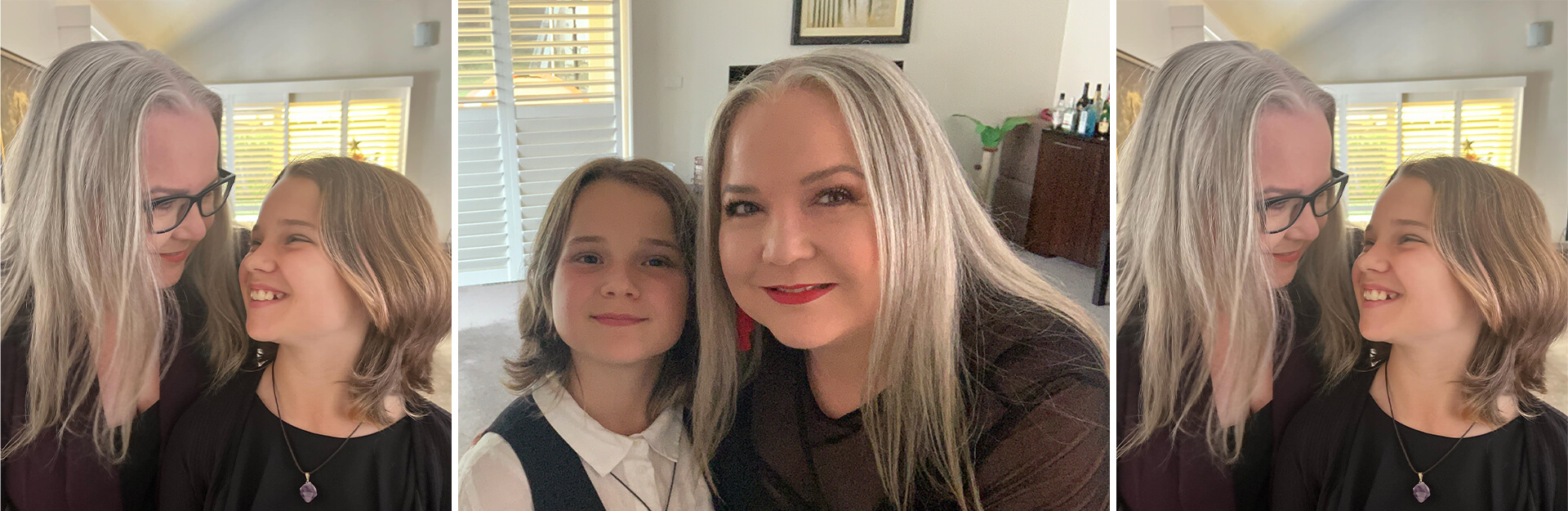 A woman with long gray hair and glasses smiles at a child with short hair, both sharing a joyful moment in a bright room.