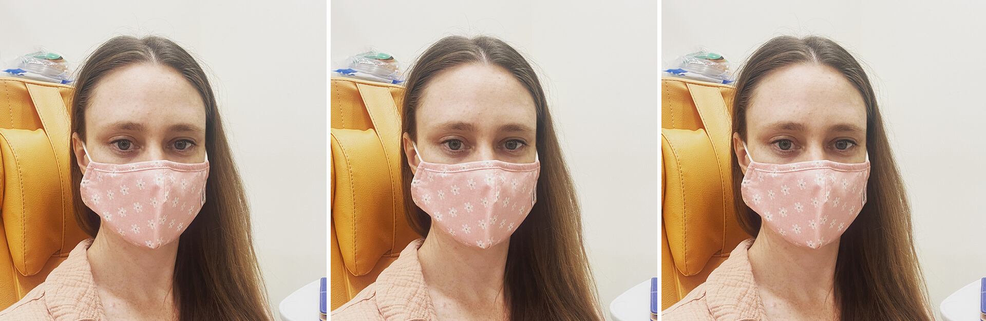 A woman with long hair wears a pink floral mask, sitting in a medical setting with orange furniture.
