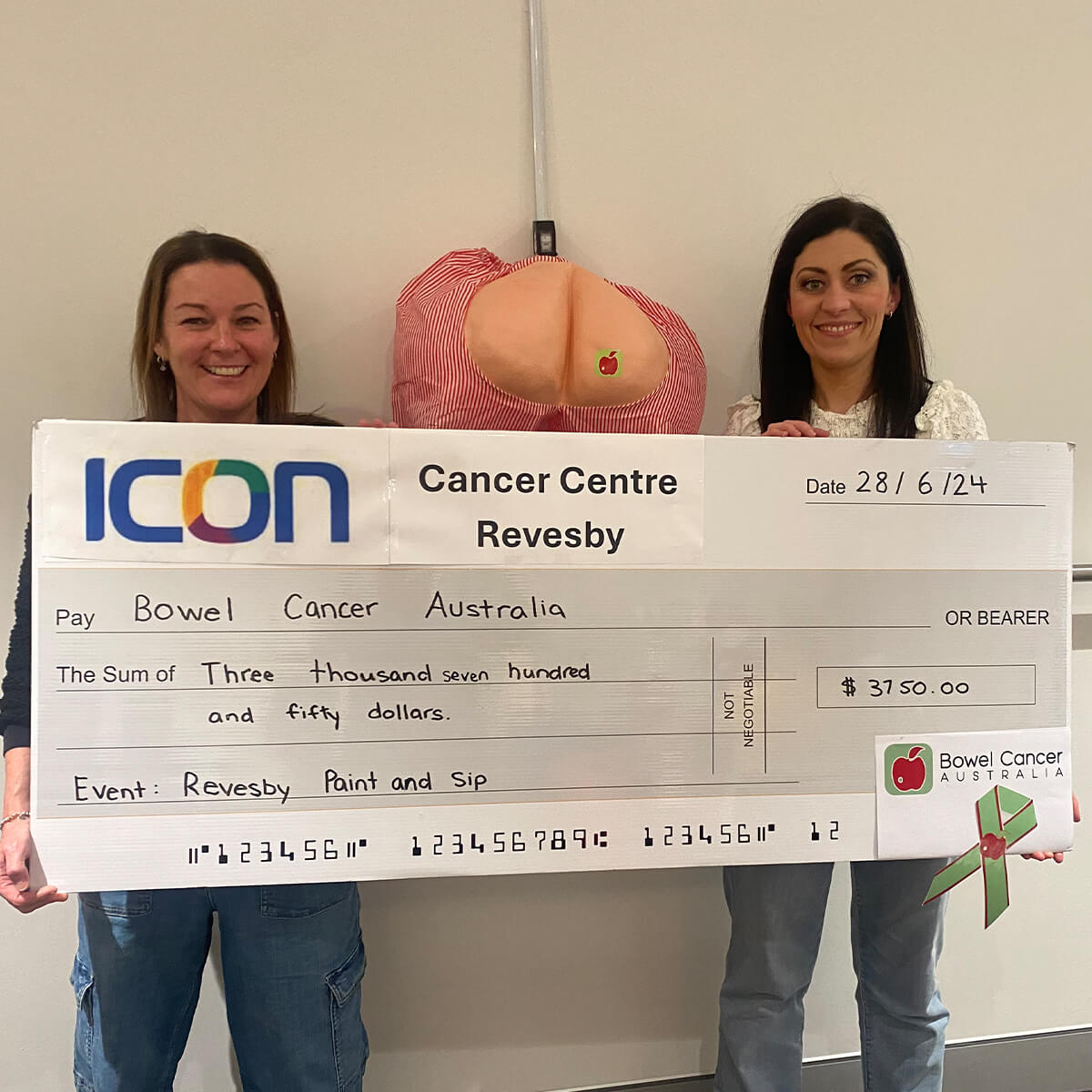 Two women hold a large check for $3,750 made out to Bowel Cancer Australia at the Icon Cancer Centre in Revesby.