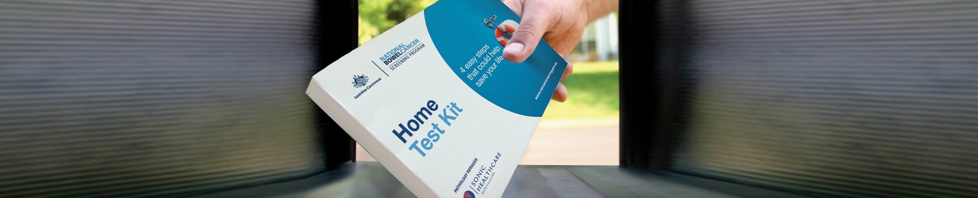 A hand is placing a "Home Test Kit" box into a mailbox.
