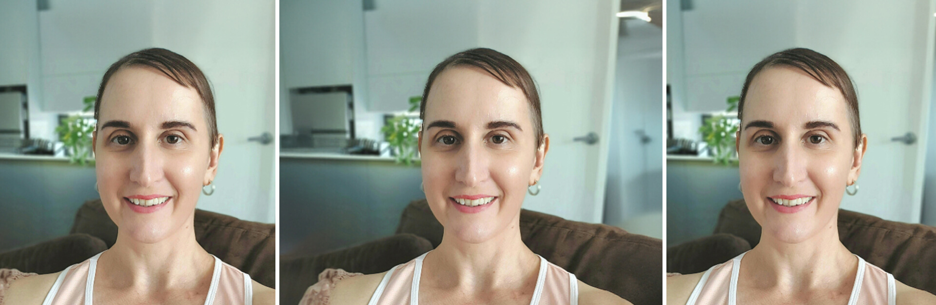 A woman with short hair smiles at the camera, sitting on a couch with a kitchen background.