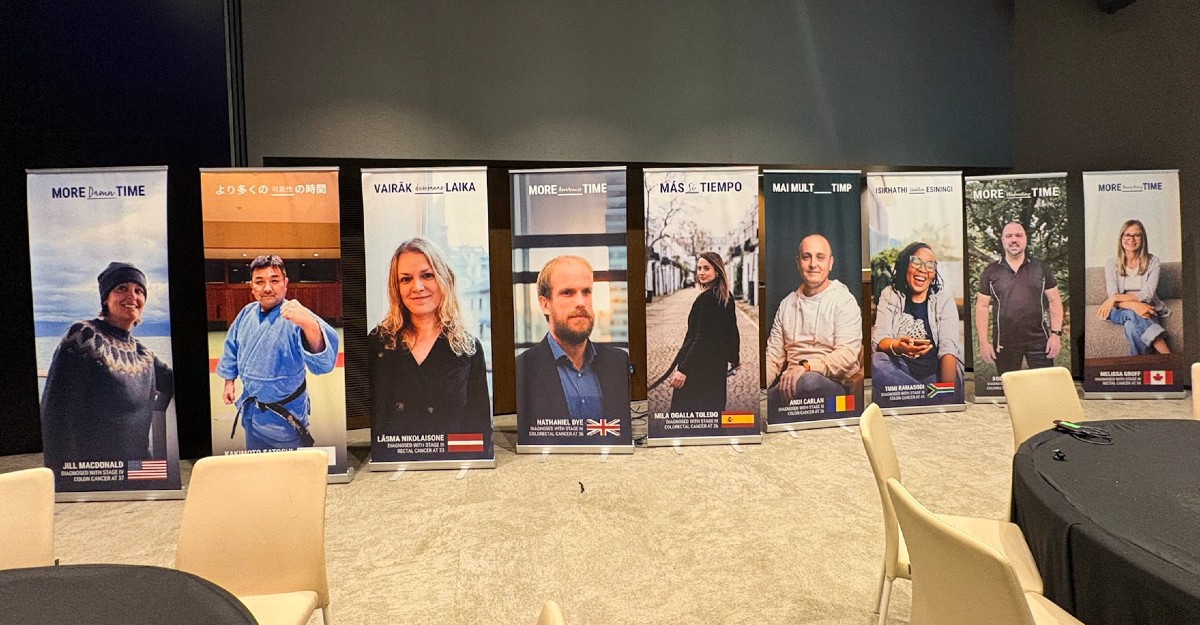 Eight standing banners featuring diverse individuals with text in various languages, set in a conference room.