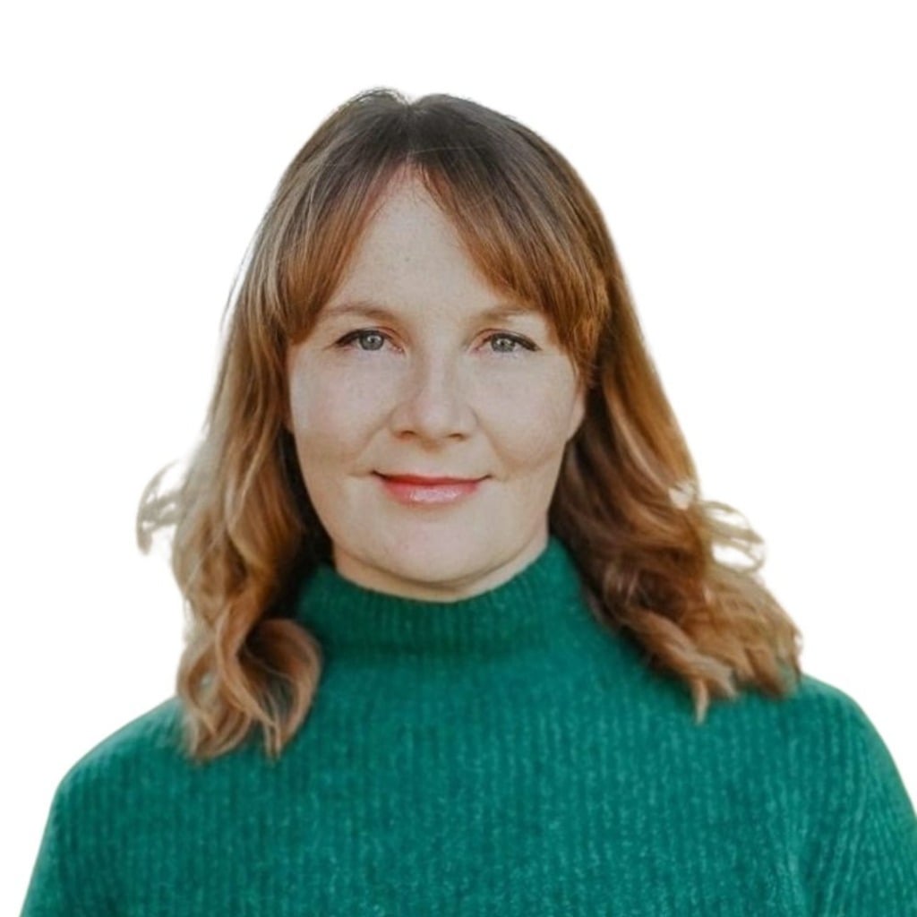 A woman with shoulder-length brown hair smiles, wearing a green sweater, against a white background.