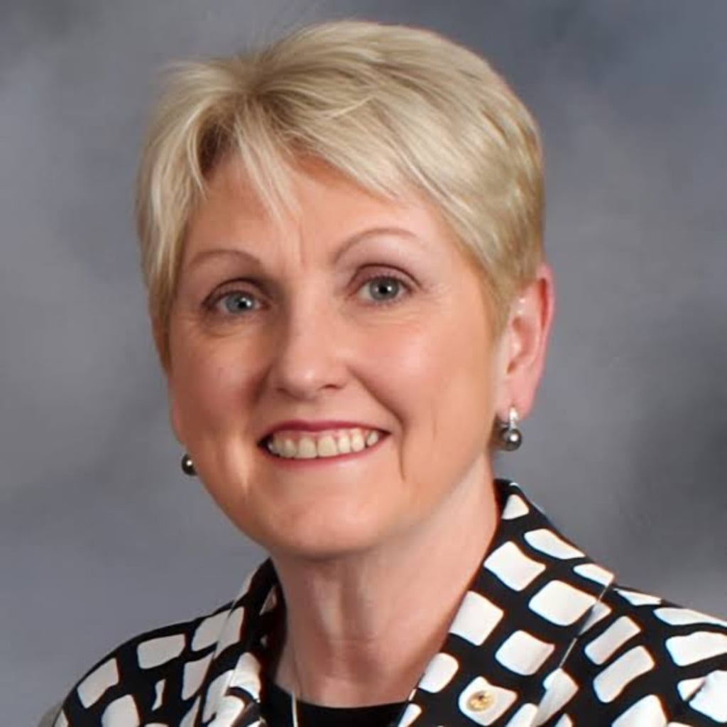 A smiling woman with short blonde hair wearing a patterned black and white blazer, representing the early-onset bowel cancer centre of research excellence.