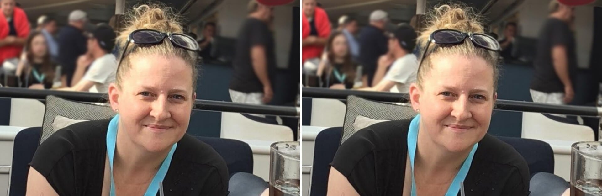 A woman with curly hair smiles, wearing a black top and a blue lanyard, seated at a table in a crowded setting.