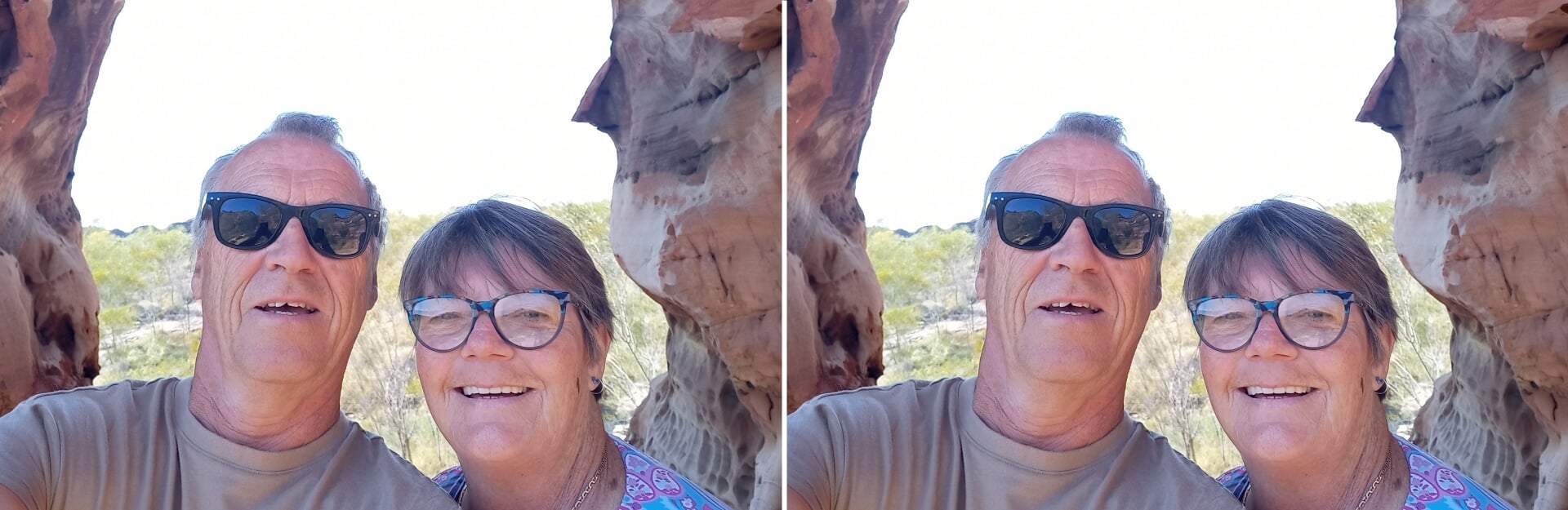A man and a woman smiling for a selfie in a natural rock formation with greenery in the background.